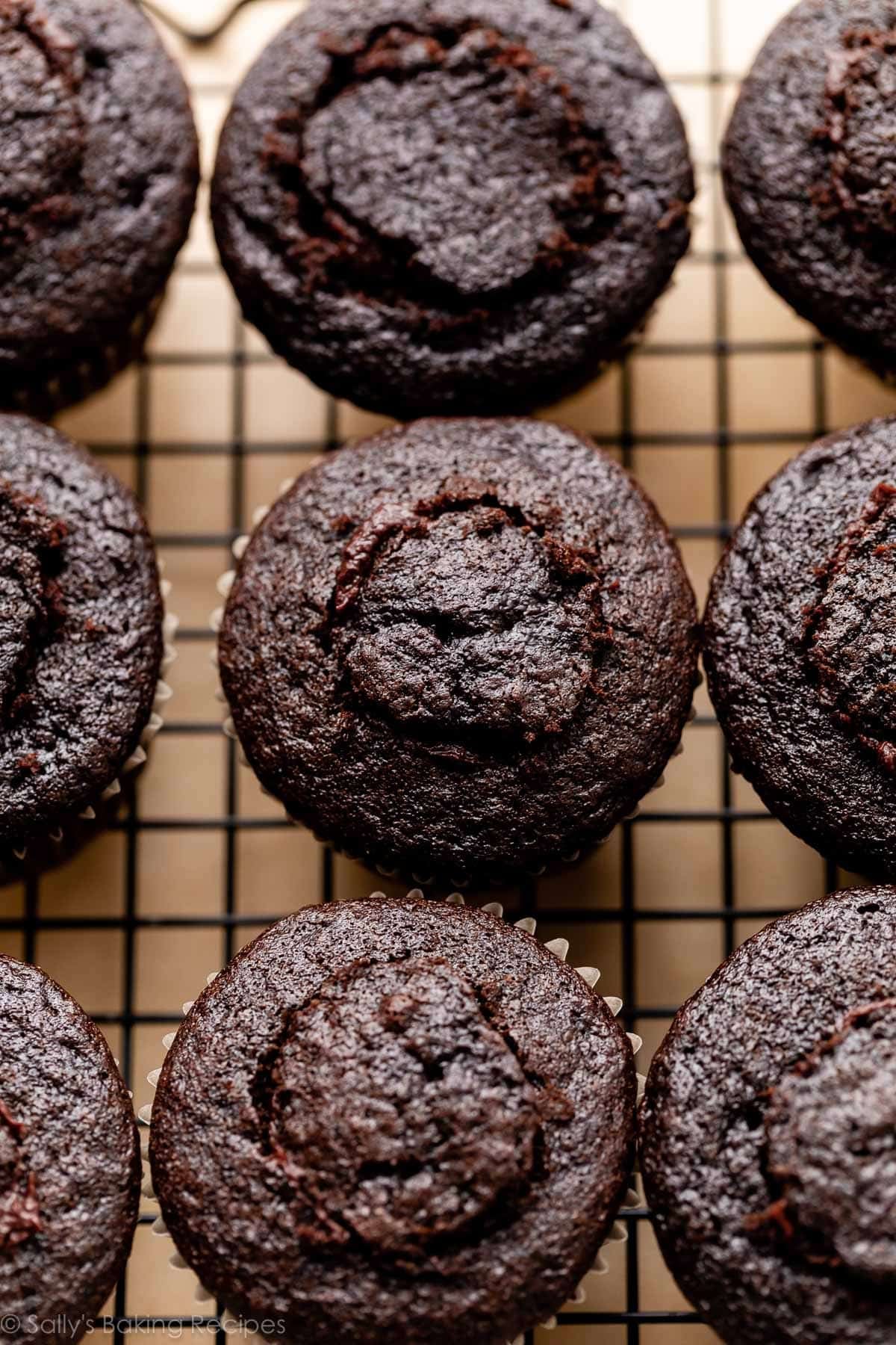 chocolate cupcakes on cooling rack with centers cut open, filled, and topped again.