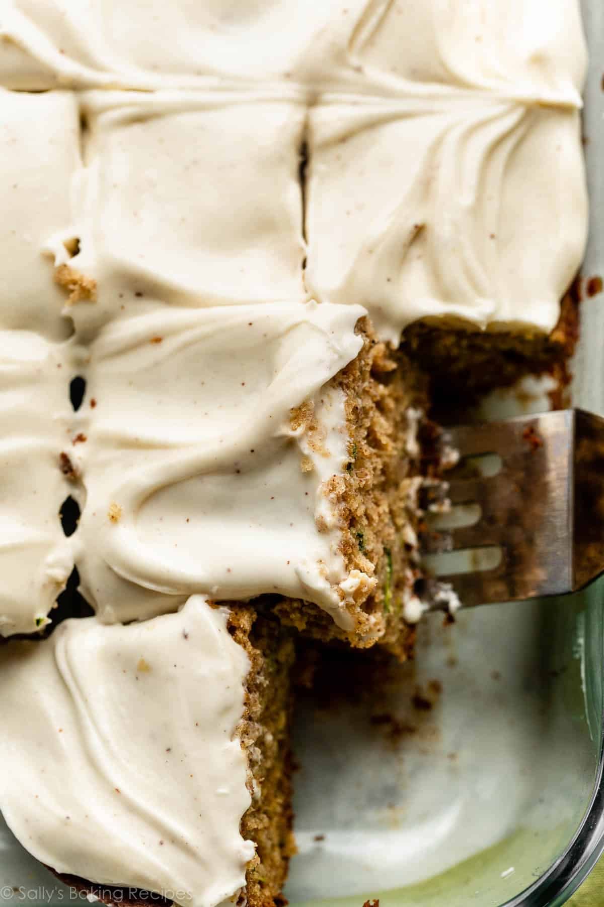 sheet cake with brown butter cream cheese frosting and spatula removing a slice.