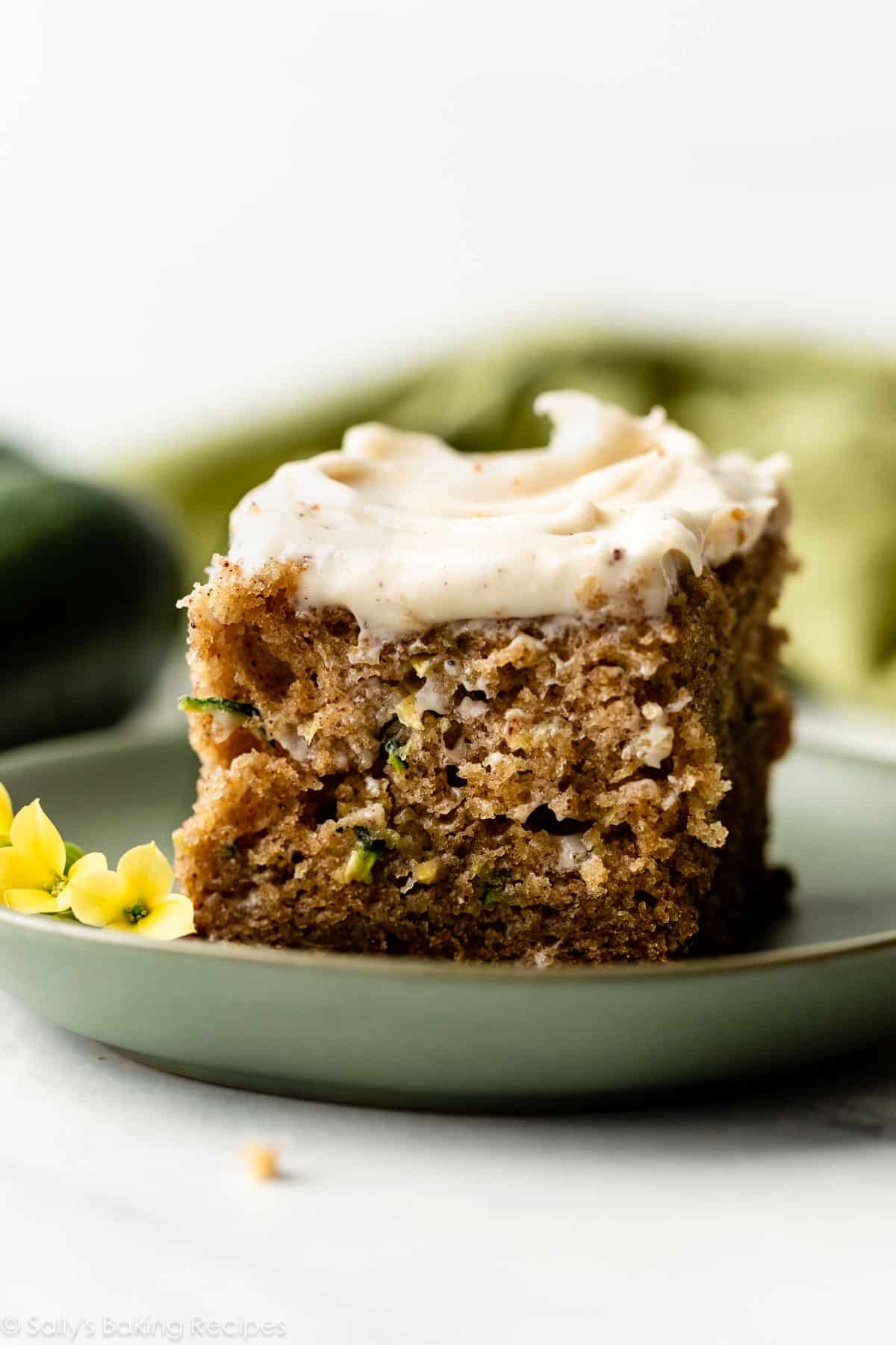 zucchini cake with brown butter cream cheese frosting on green plate.