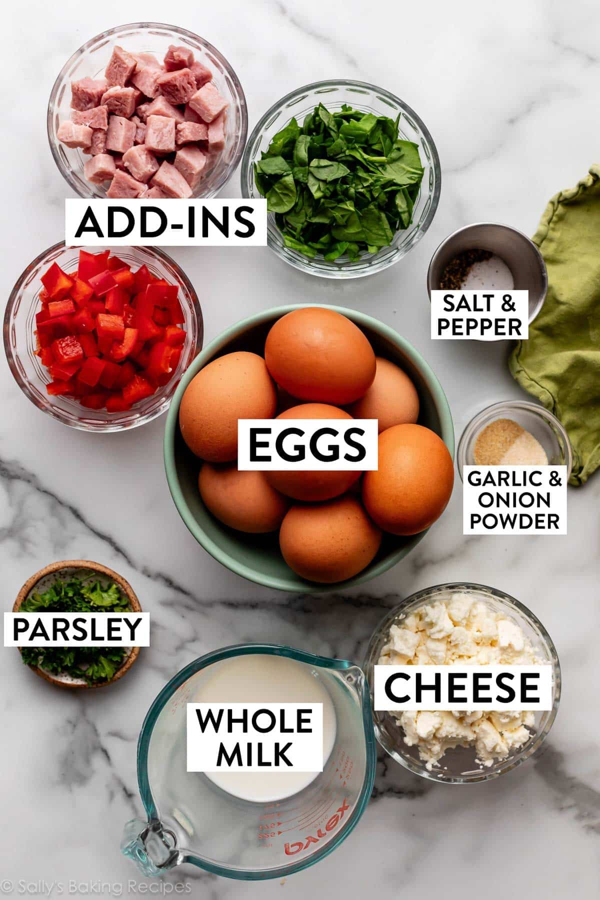 ingredients on counter including chopped ham, red pepper, cheese, spinach, and milk in a liquid measuring cup.