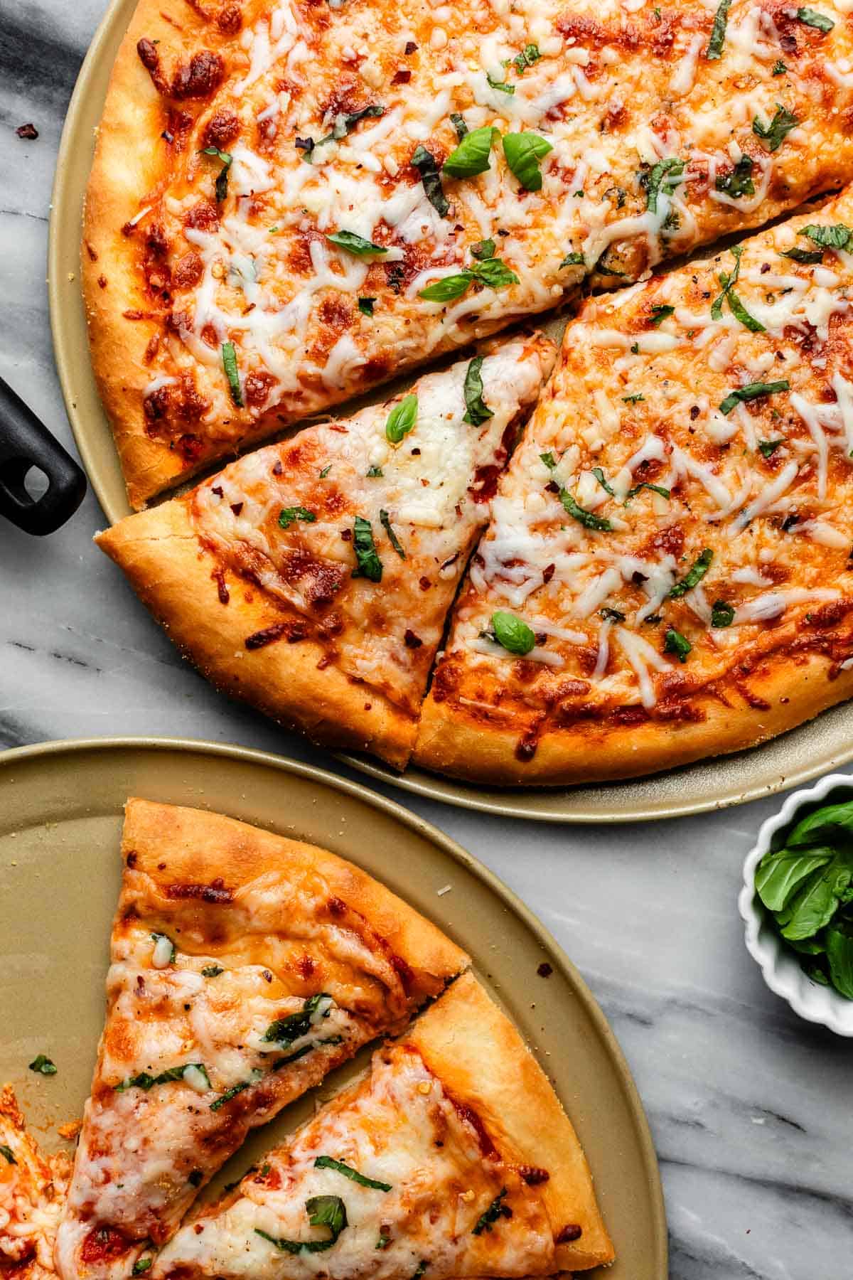 pizzas with cheese topping on gold pizza pan.