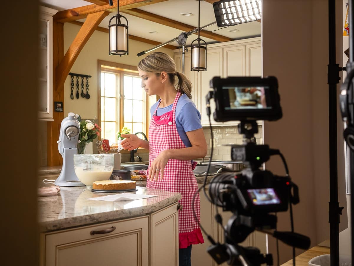 Sally behind cameras with cheesecake.