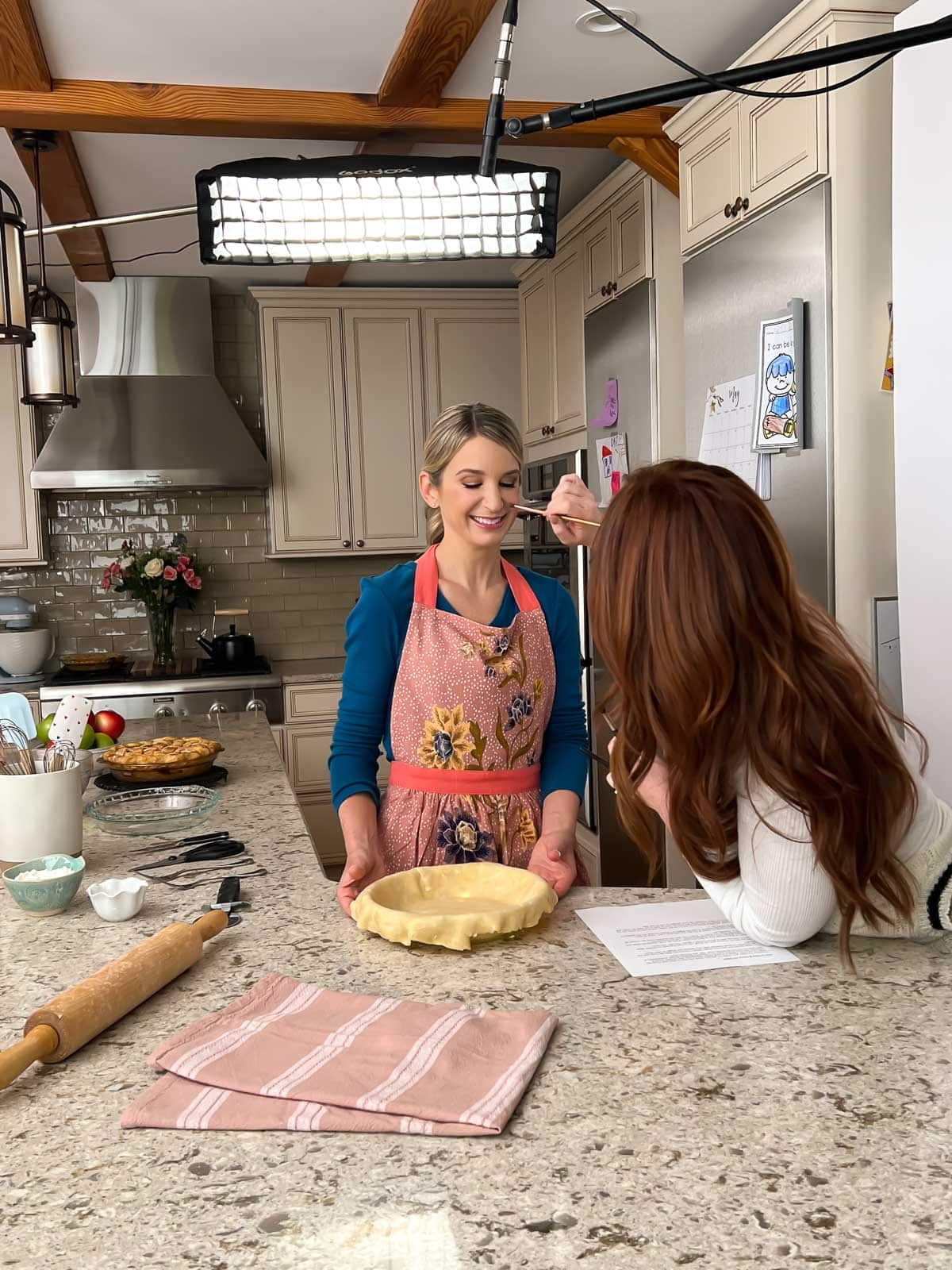 Sally behind the scenes with makeup artist applying makeup on set.