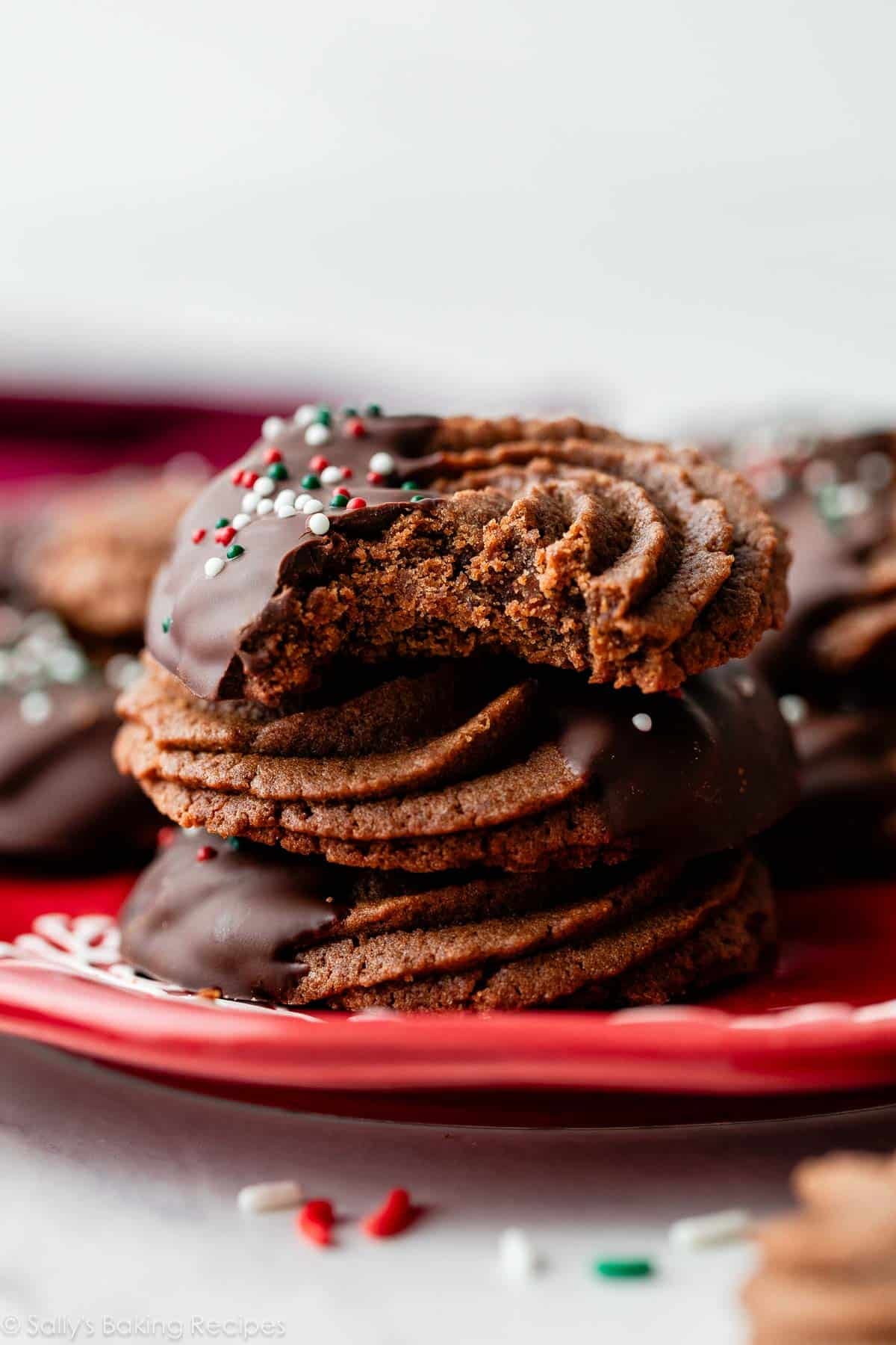 stack of piped chocolate butter cookies and the top has a bite taken out.