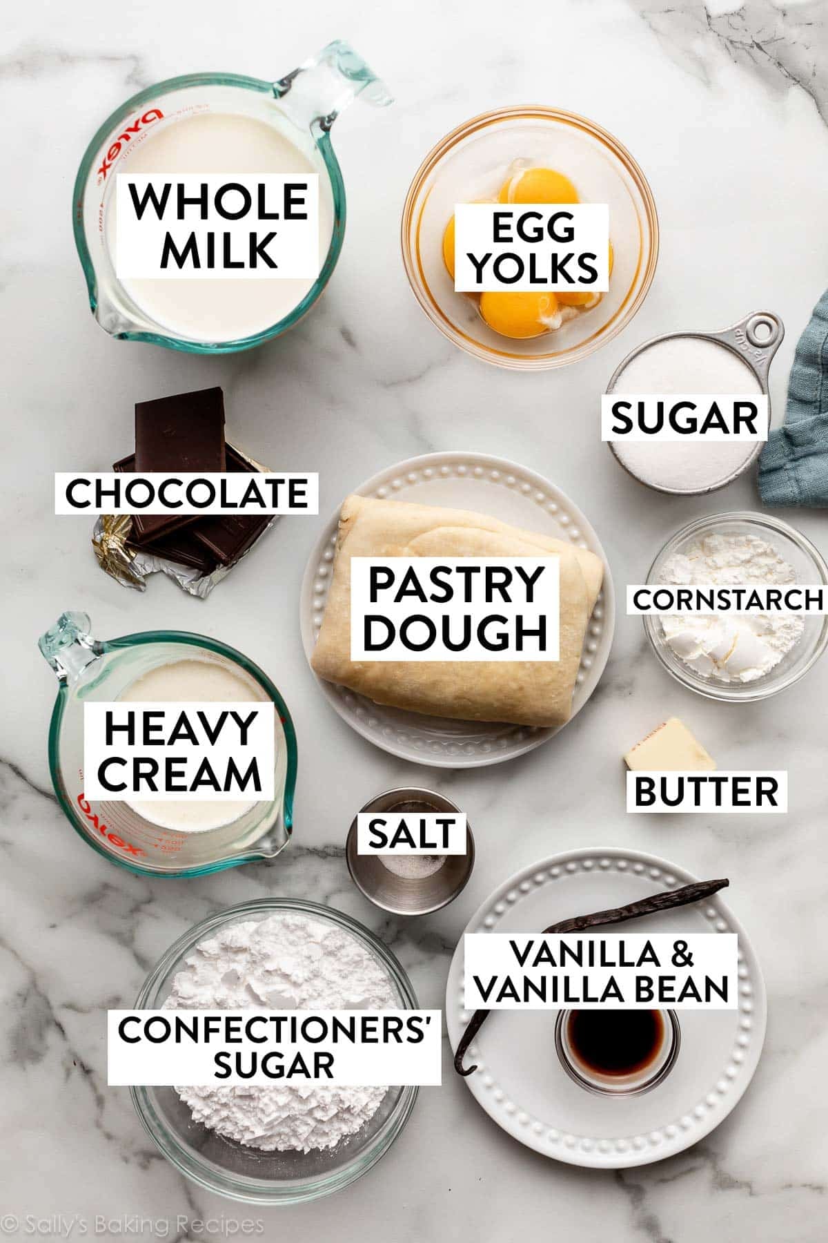 ingredients measured on marble counter including egg yolks, cornstarch, butter, pastry dough, heavy cream, chocolate, and milk.