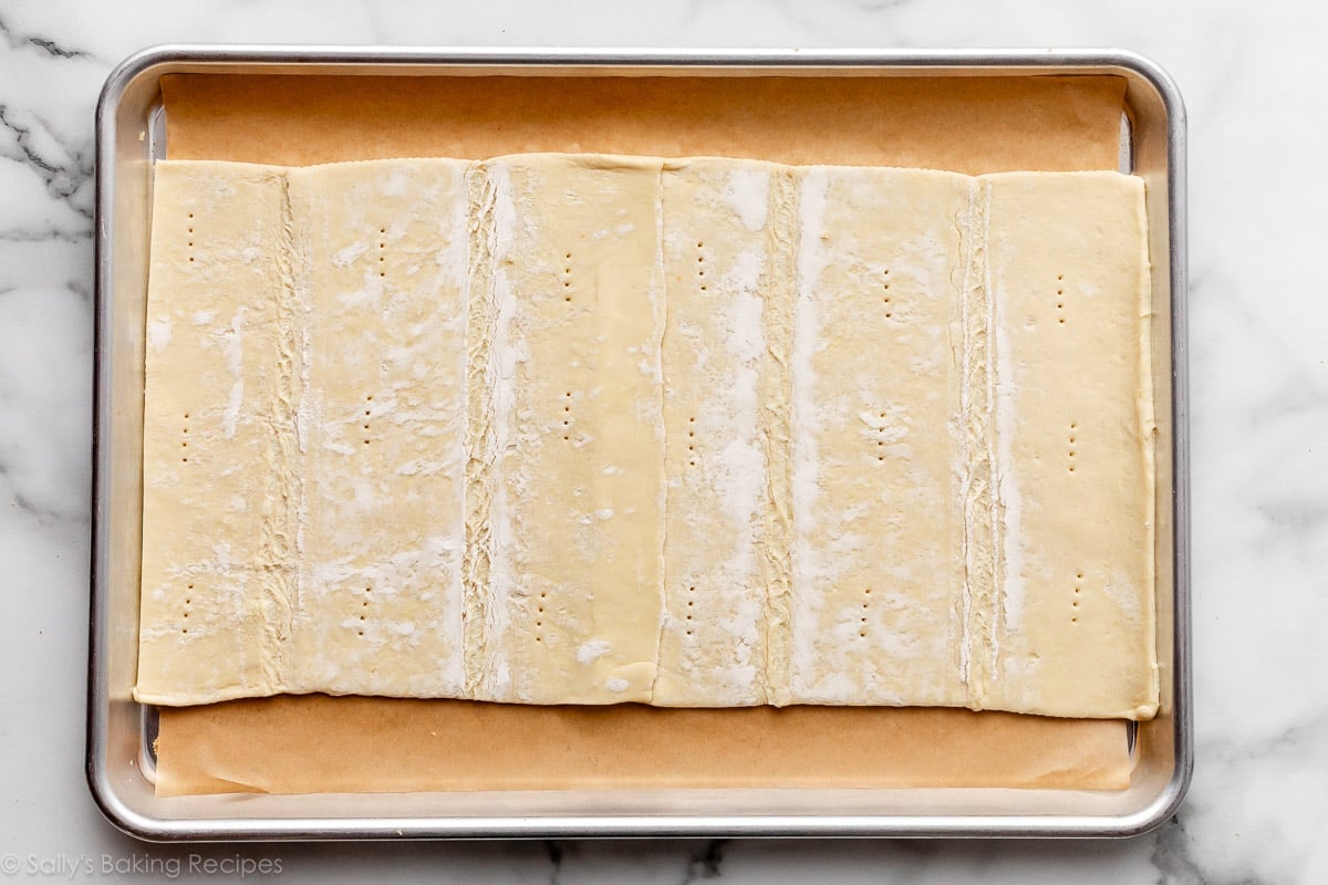 rolled out store-bought puff pastry docked with fork on top of lined baking sheet.