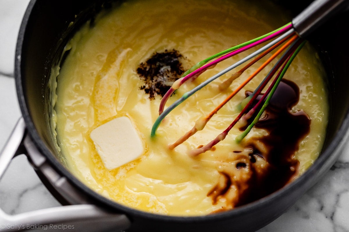 butter and vanilla on top of cooked pastry cream with rainbow whisk.