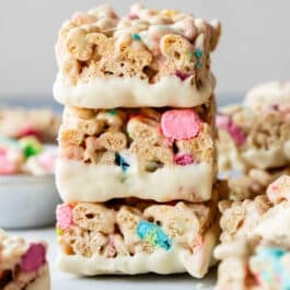 stack of 3 white chocolate dipped Lucky Charms cereal treats.