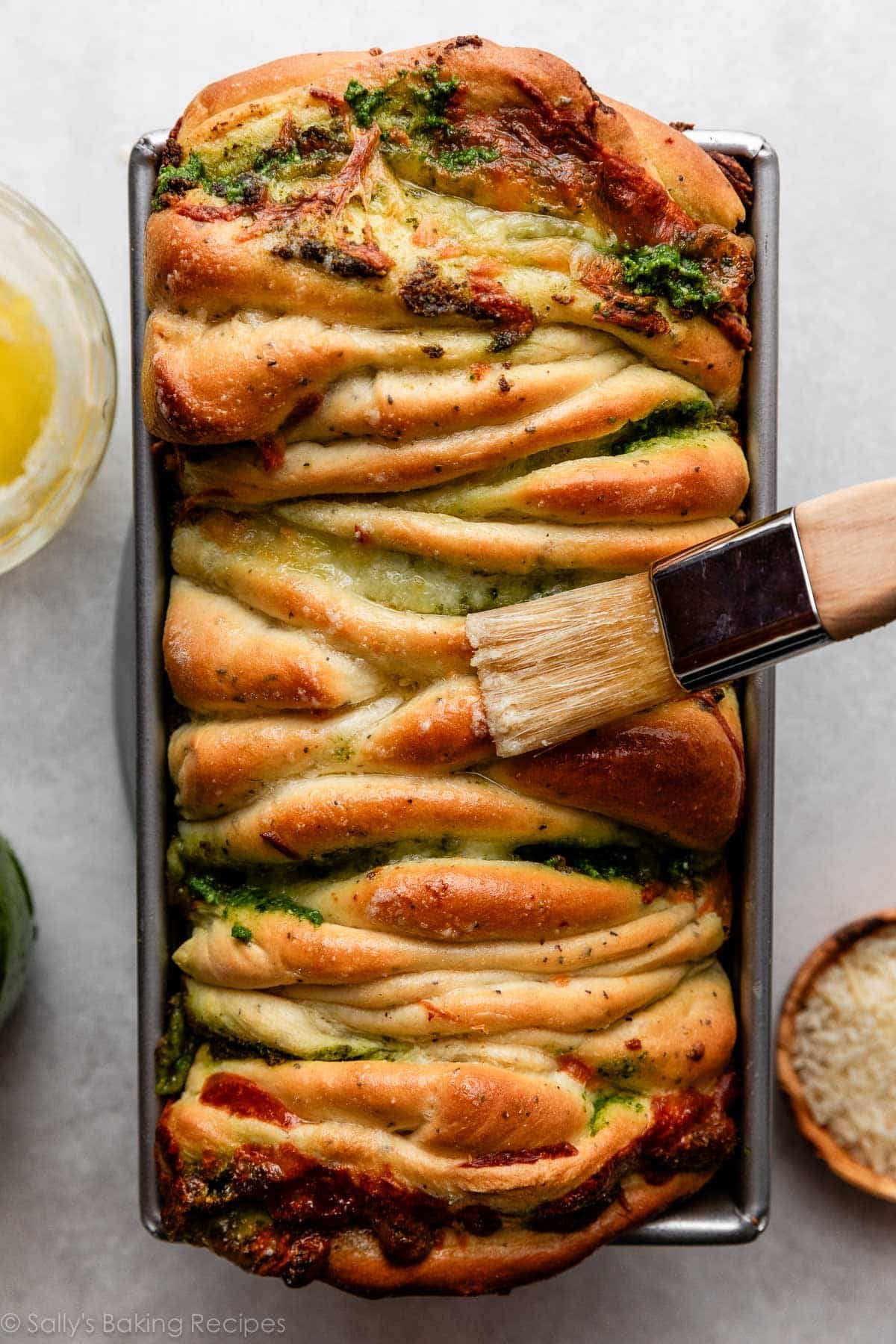 brushing melted butter on pesto bread.
