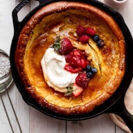dutch baby with strawberry sauce, fresh berries, and whipped cream.