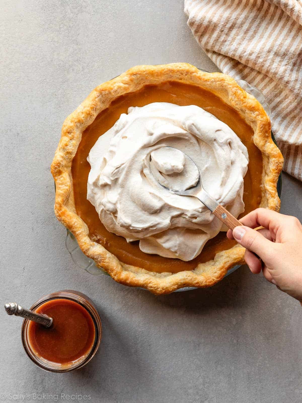 spreading whipped cream on top of butterscotch pie.