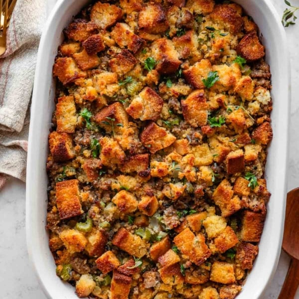 cornbread stuffing with sausage and herbs in white casserole dish.