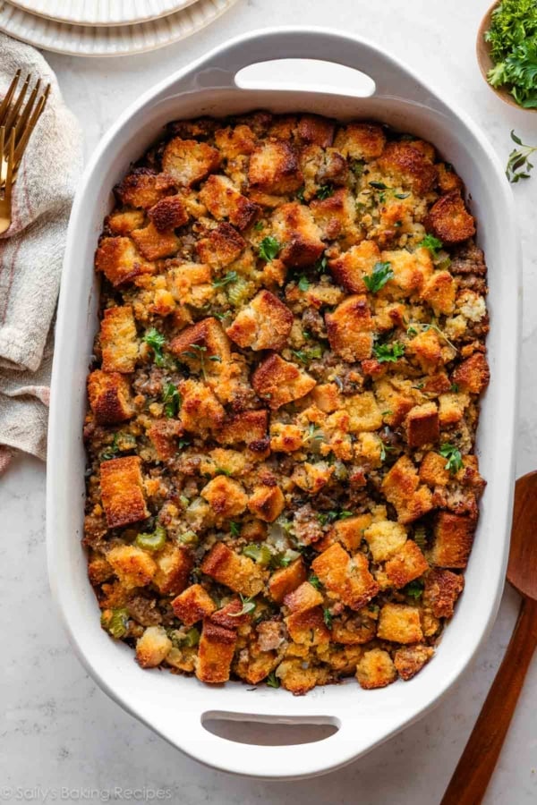 cornbread stuffing with sausage and herbs in white casserole dish.