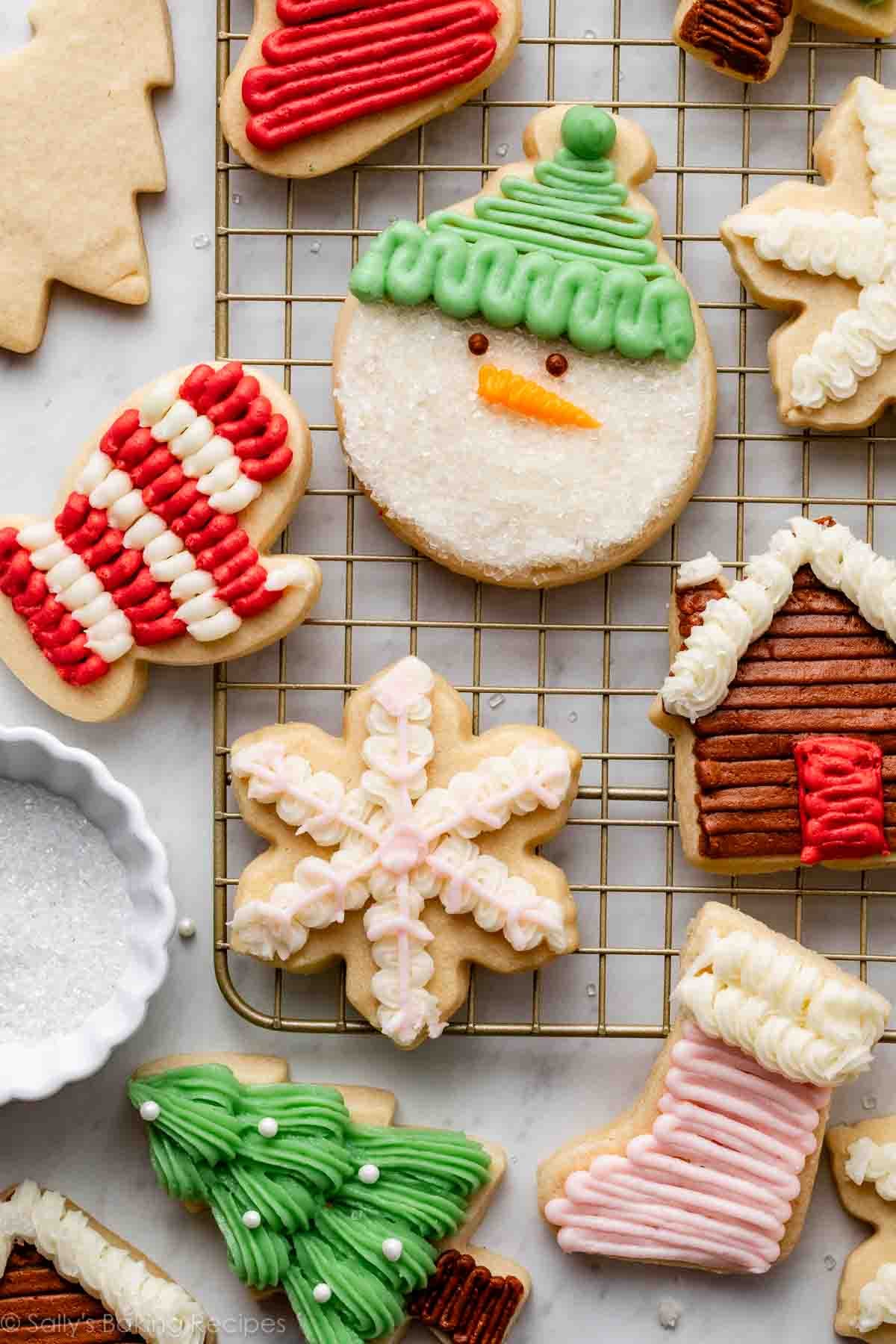 Christmas sugar cookies decorated with cookie decorating buttercream frosting on gold cooling rack.