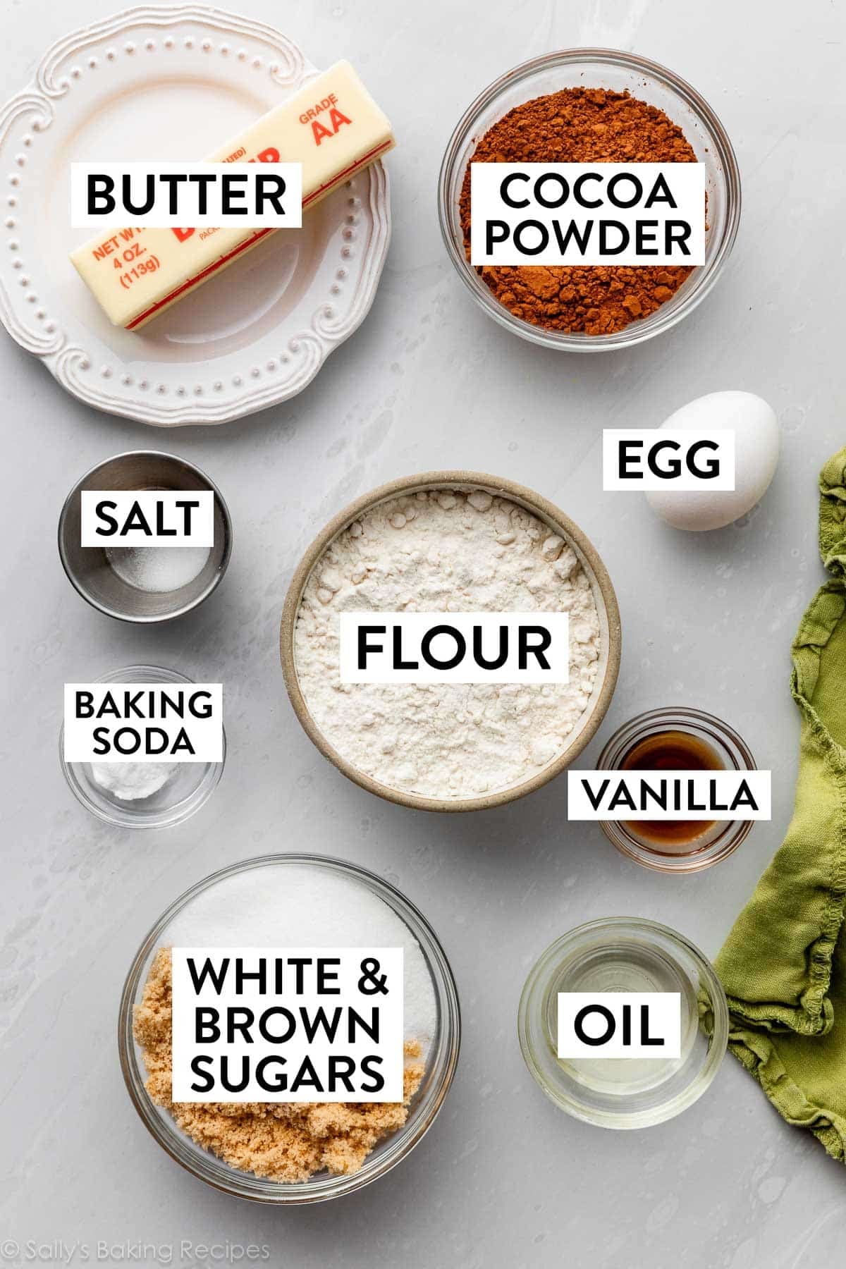 ingredients on marble counter including butter, white and brown sugars, flour, egg, vanilla, and oil.