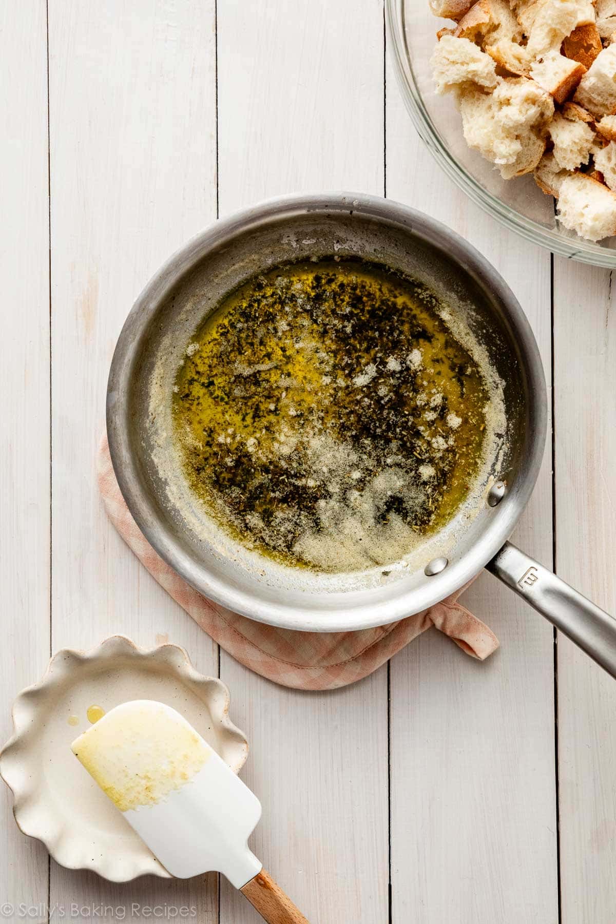 small skillet with melted butter, oil, and herbs in it.