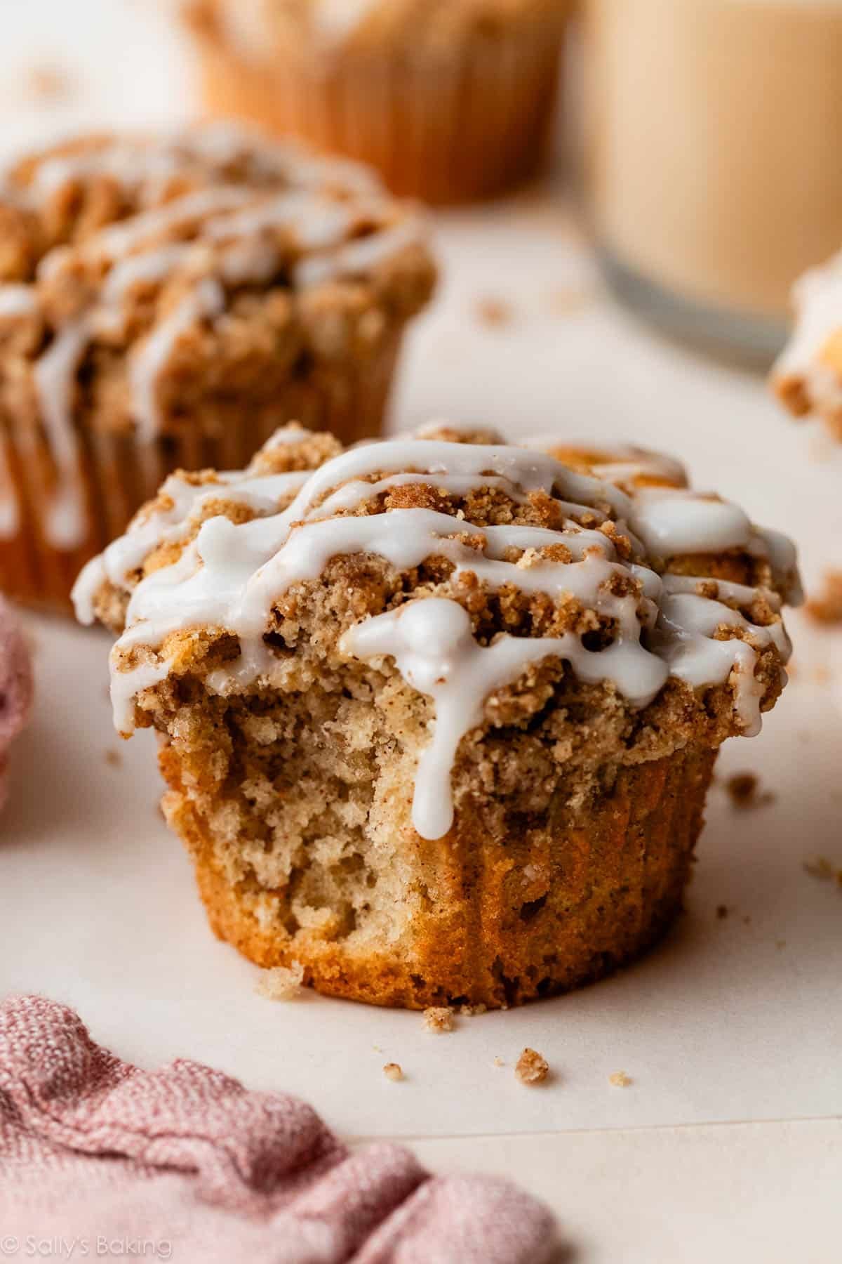 crumb cake muffin with icing with bite taken out of it.