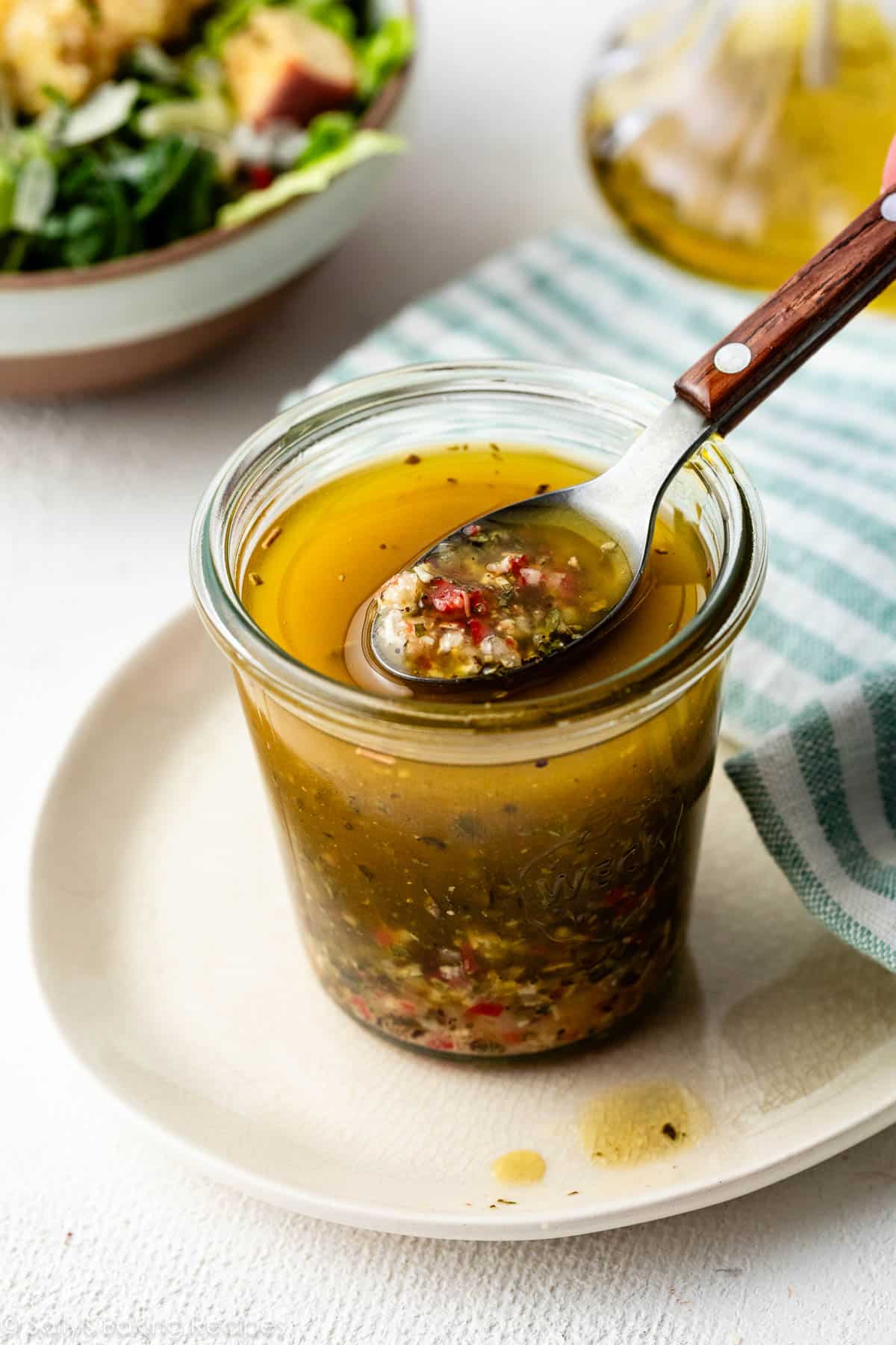 jar of homemade Italian dressing with a spoon.
