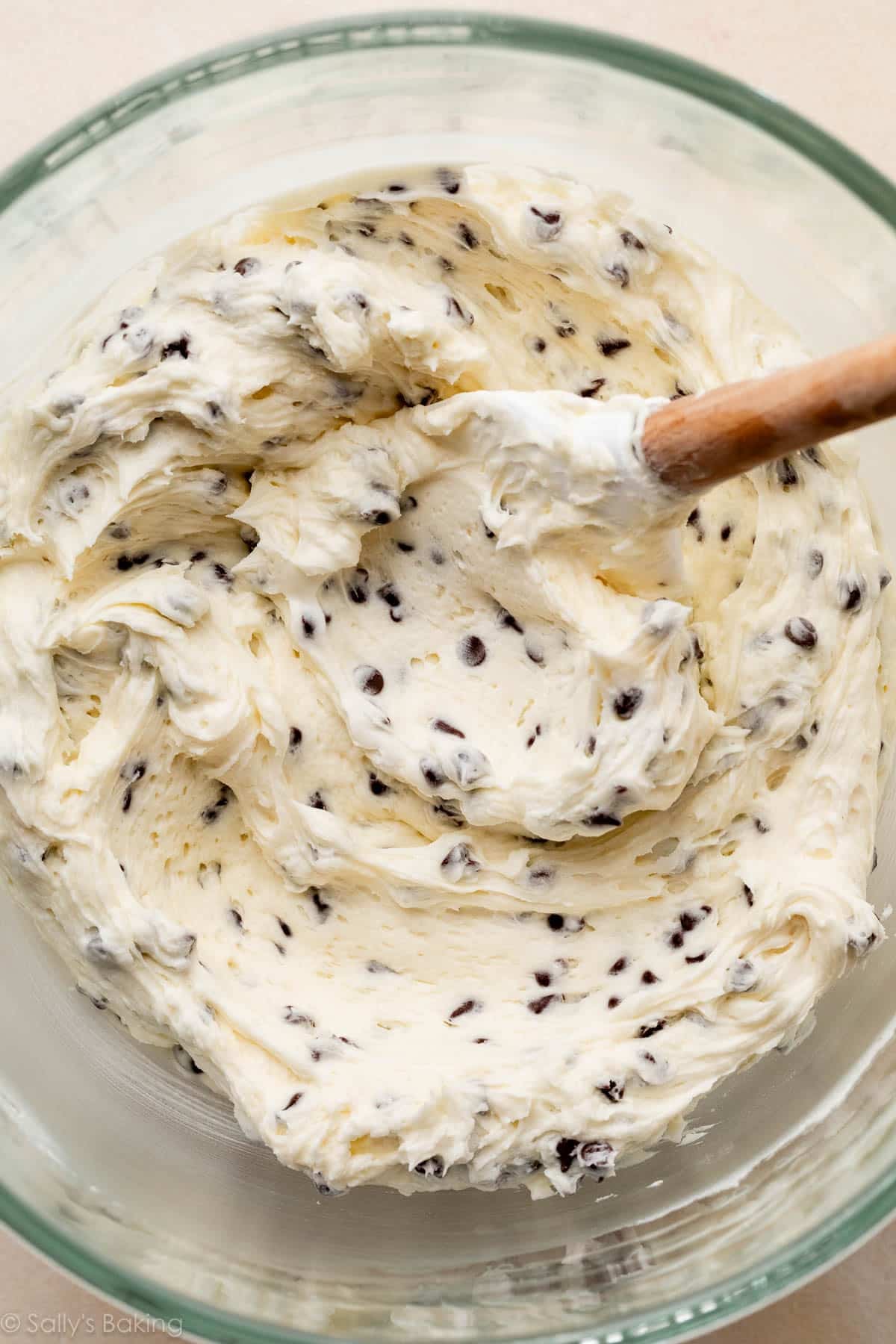 vanilla buttercream with chocolate chips in large glass bowl with spatula.