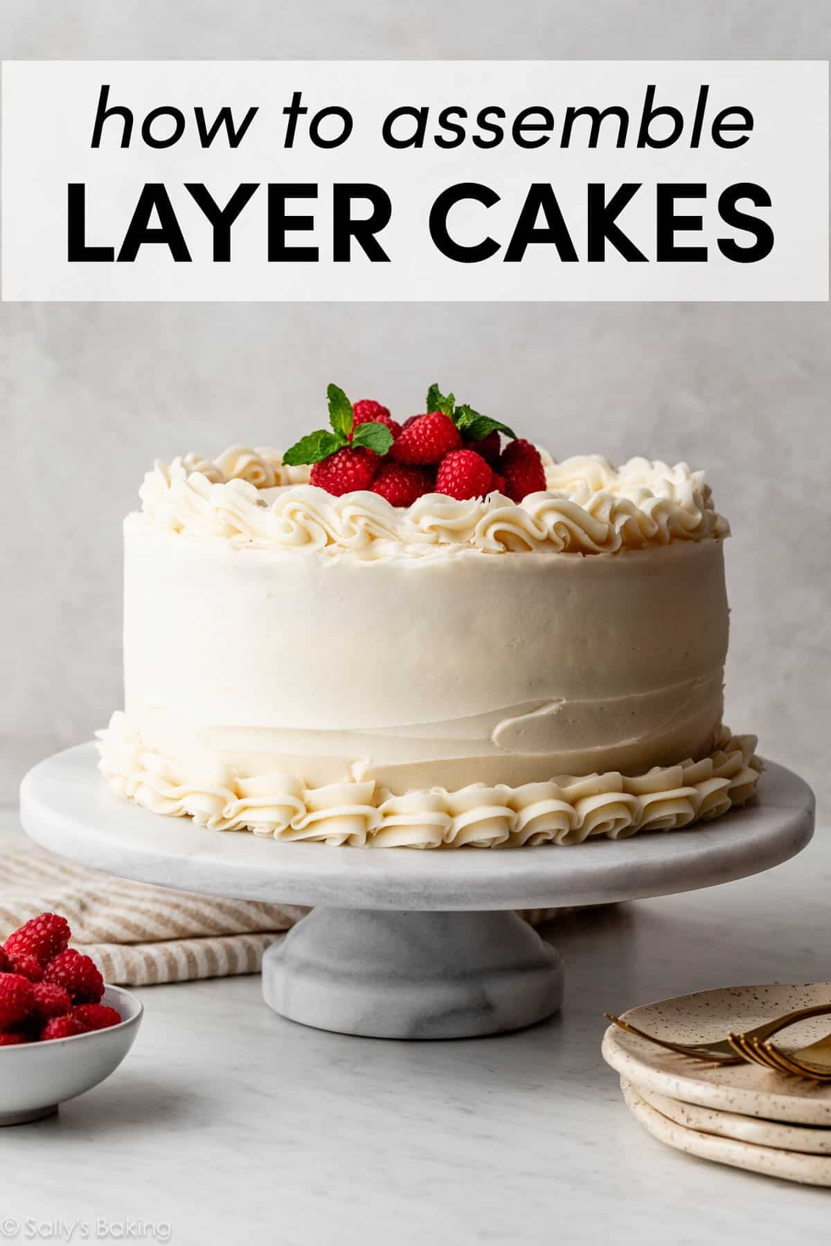 vanilla layered cake with piped vanilla frosting and fresh raspberries and mint on top.