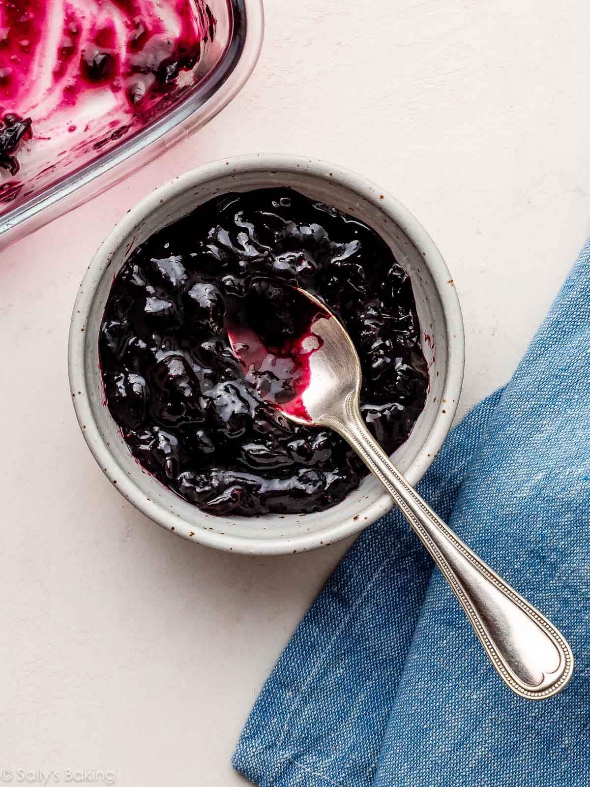 homemade blueberry jam filling in small bowl with spoon.