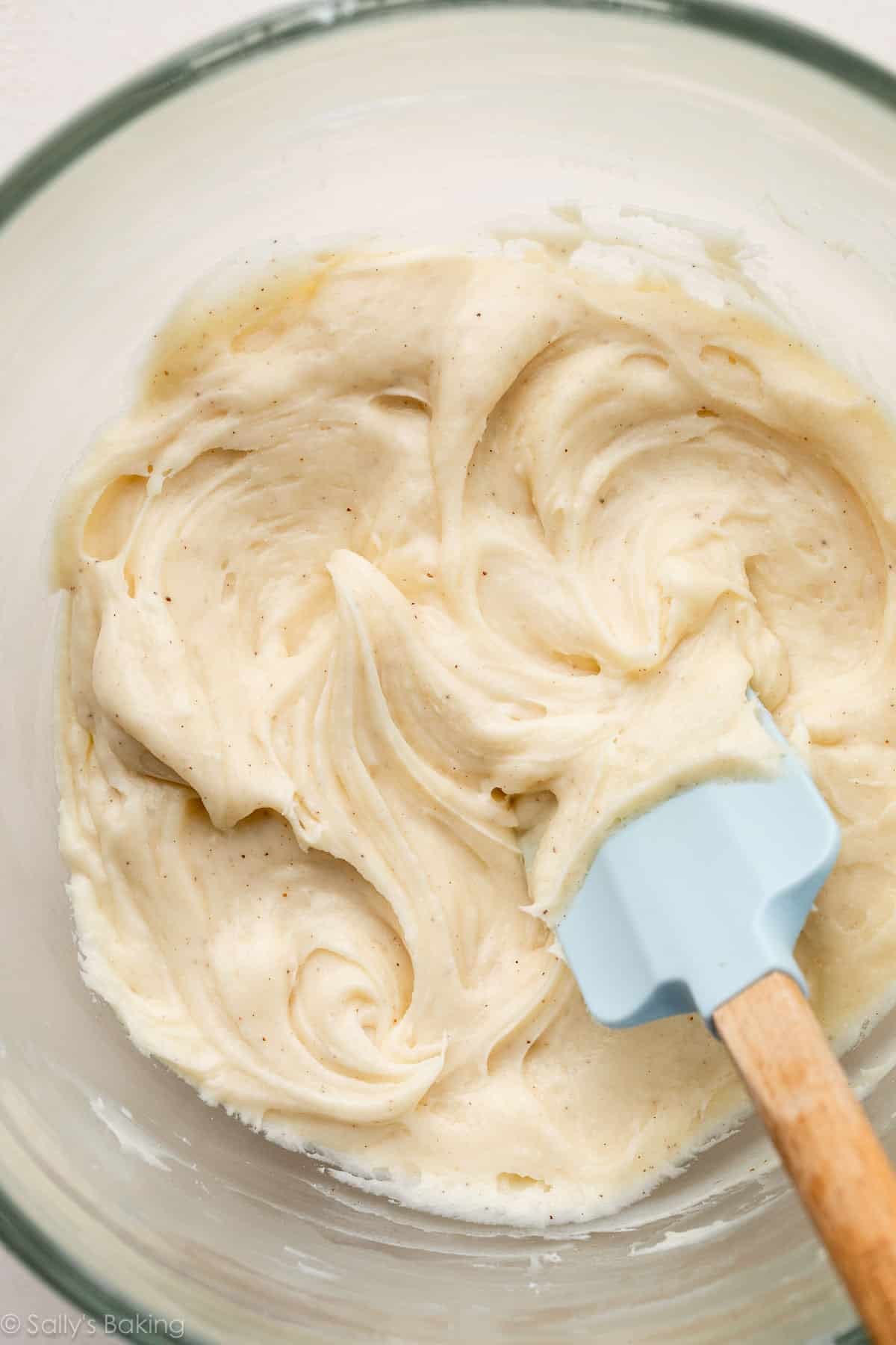 browned butter cream cheese frosting in bowl with blue spatula.
