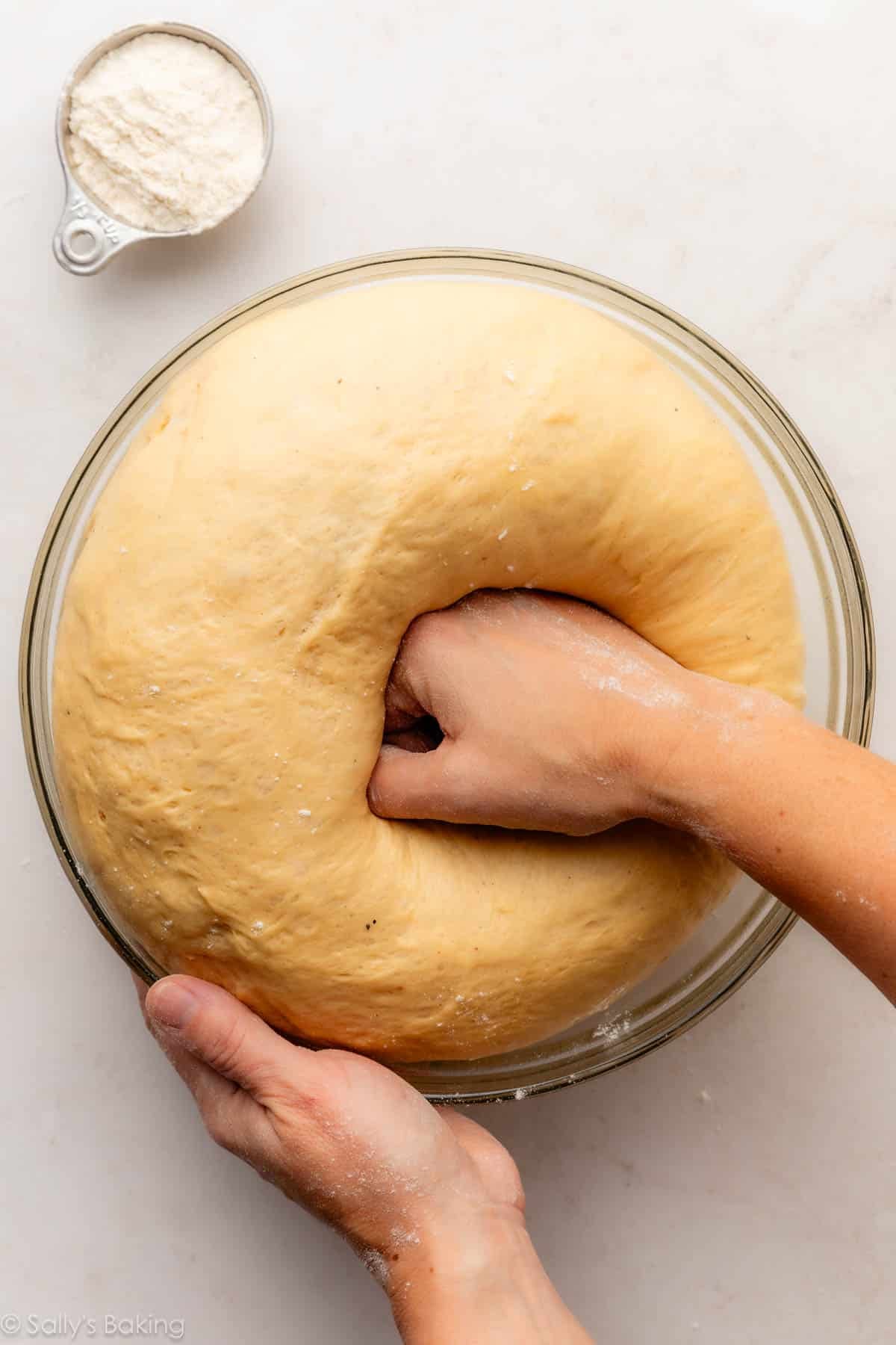 hand punching down dough.