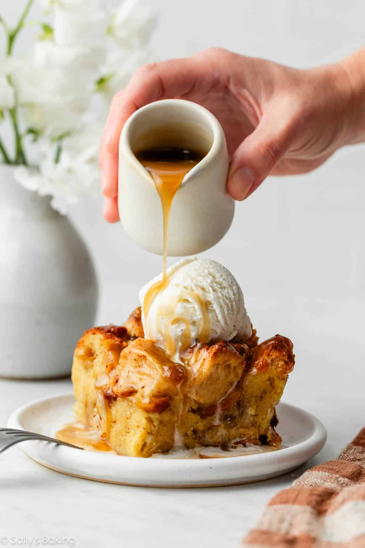 bread pudding with butter rum sauce being poured on top.