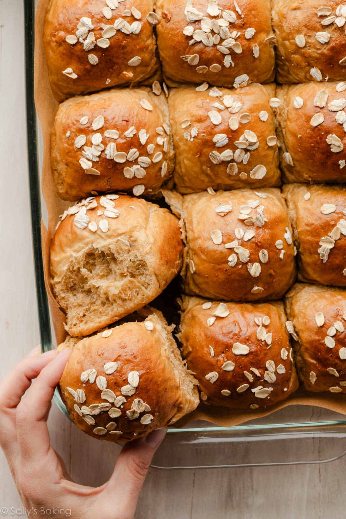hand pulling away molasses oatmeal roll from batch.