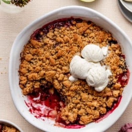 pear berry crumble in white serving dish with vanilla ice cream.