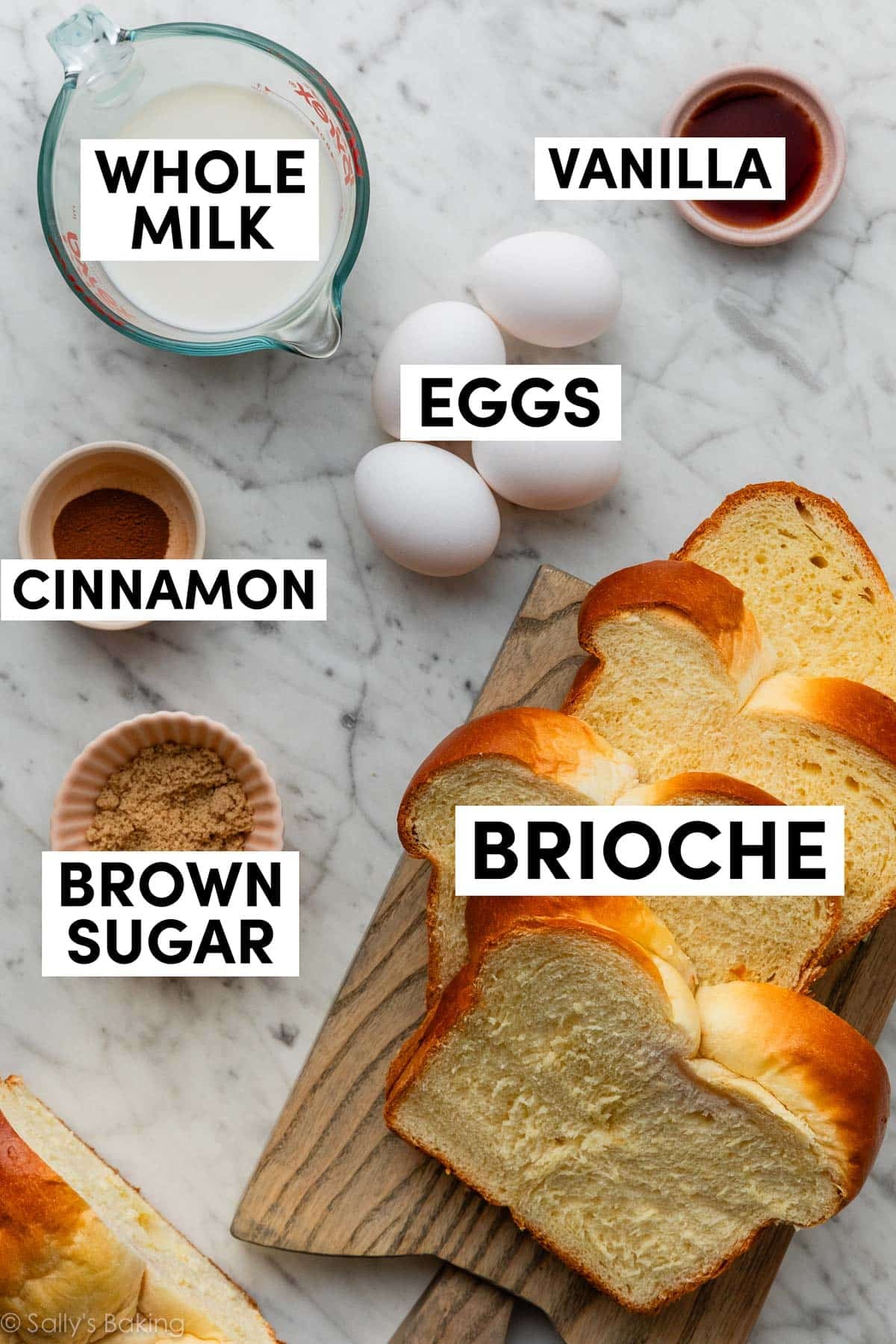 ingredients on marble counter including eggs, vanilla, cinnamon, brown sugar, and milk.