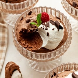 chocolate mousse in glass cups with whipped cream and raspberries.