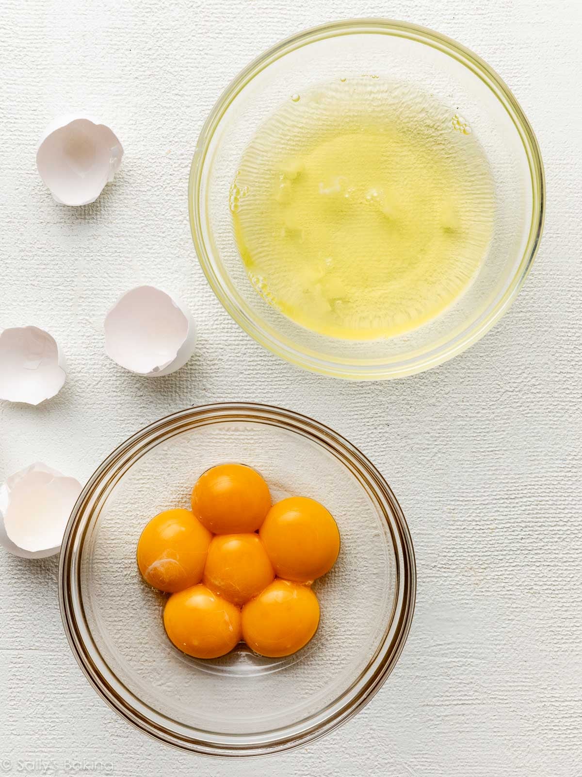 separated egg whites and yolks in separate bowls.