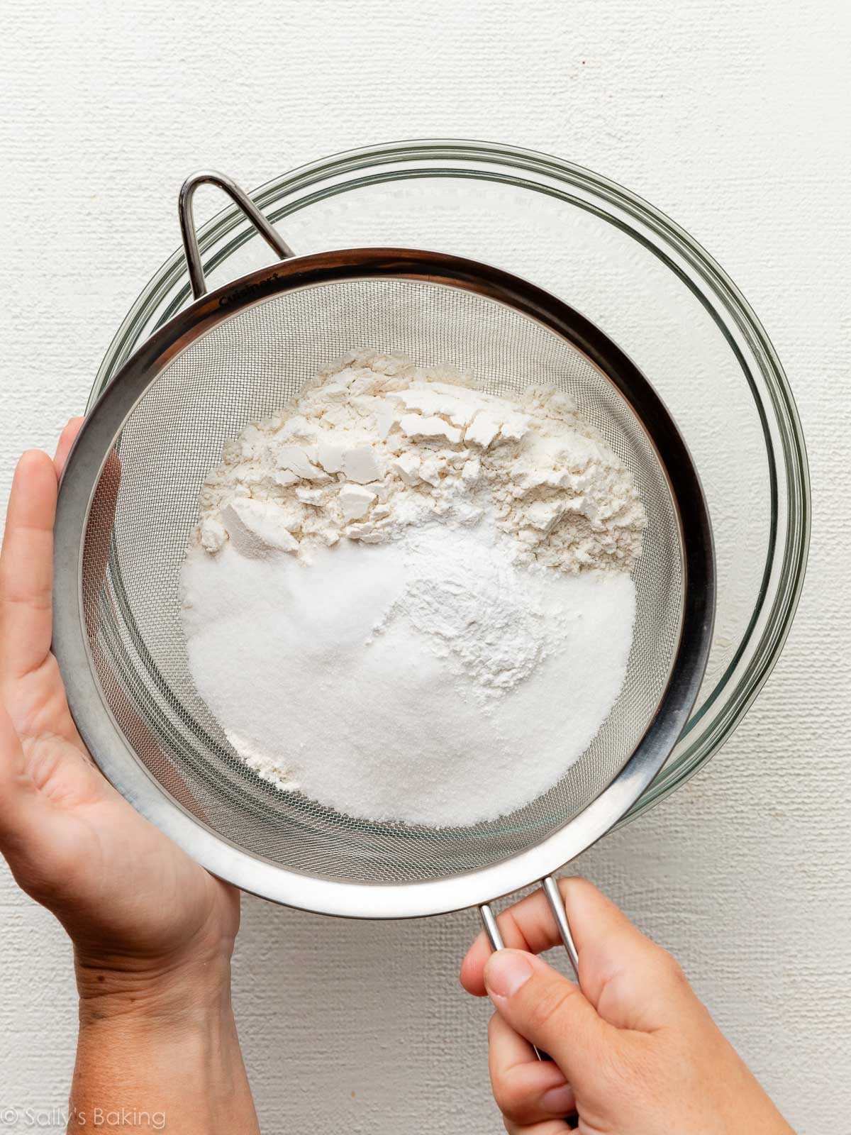 hands using sieve to sift dry ingredients.
